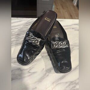 Stuart Weitzman black patent leather mules featuring a silver chain link